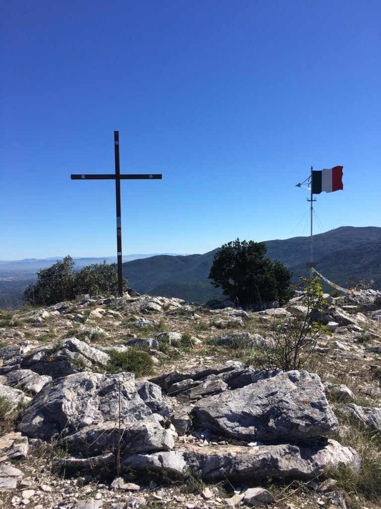 Croce di vetta su un cumulo di sassi, cielo azzurro